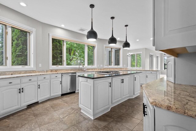 kitchen with dark stone counters, white cabinetry, stainless steel gas range oven, and decorative light fixtures