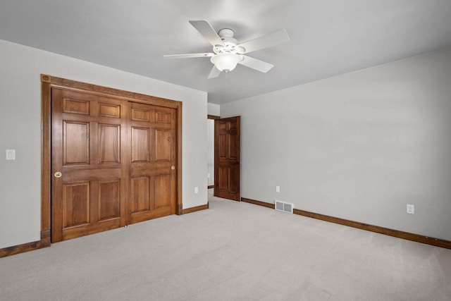 unfurnished bedroom featuring light colored carpet, ceiling fan, and a closet