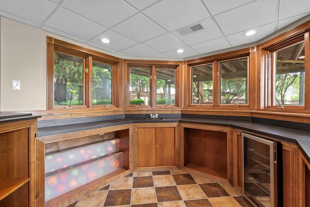 interior space featuring beverage cooler, a paneled ceiling, and a wealth of natural light