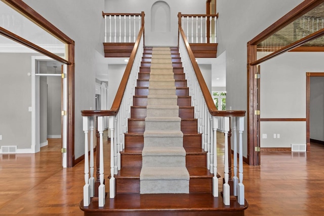 stairway featuring wood-type flooring and a high ceiling