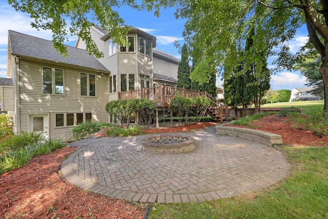 back of house with a wooden deck, a patio, and an outdoor fire pit