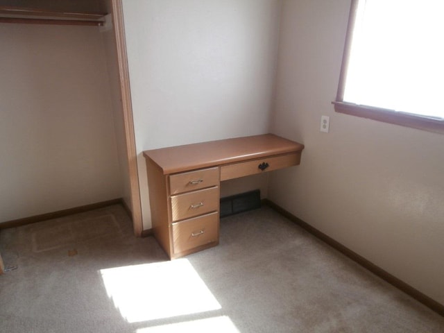 unfurnished bedroom with light carpet, visible vents, baseboards, and built in study area