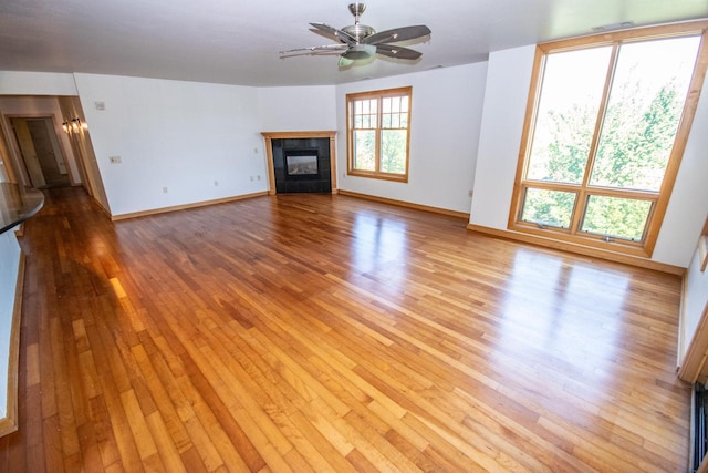 unfurnished living room featuring light wood-type flooring, ceiling fan, and a tile fireplace