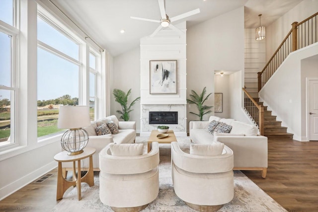 living room with high vaulted ceiling, ceiling fan, wood-type flooring, and a premium fireplace