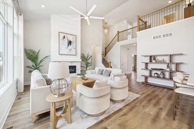 living room featuring plenty of natural light, a premium fireplace, ceiling fan, and a high ceiling