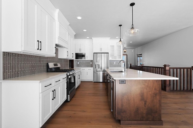 kitchen with dark wood-type flooring, an island with sink, stainless steel appliances, and sink