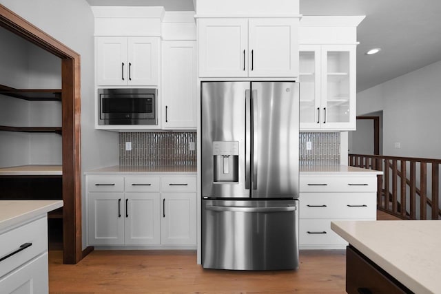 kitchen with white cabinetry, hardwood / wood-style floors, stainless steel appliances, and decorative backsplash