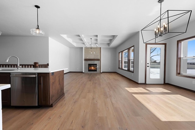 kitchen featuring light wood-type flooring, a fireplace, decorative light fixtures, dishwasher, and sink