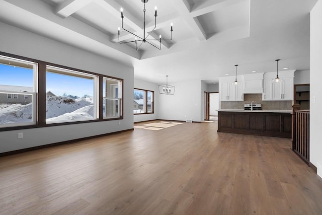 kitchen with white cabinets, hardwood / wood-style floors, a chandelier, pendant lighting, and a kitchen island with sink