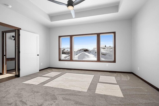 carpeted empty room featuring a tray ceiling and ceiling fan