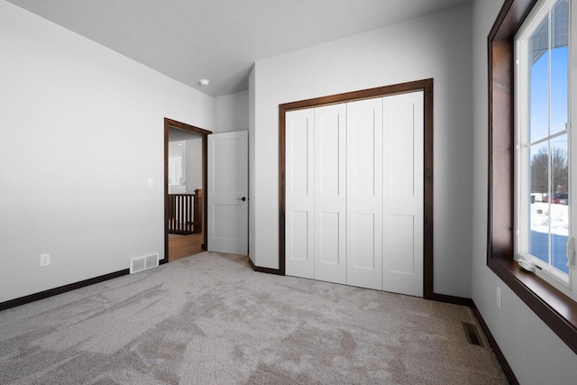 unfurnished bedroom featuring light colored carpet, a closet, and multiple windows