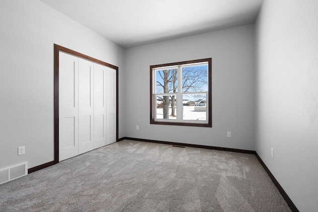 unfurnished bedroom featuring light colored carpet and a closet