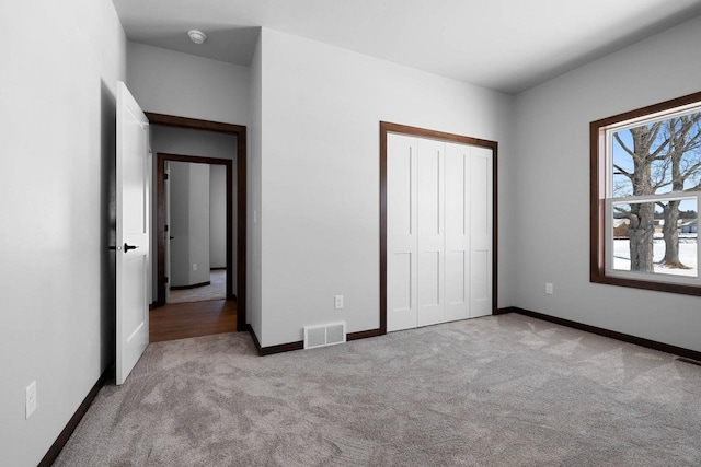 unfurnished bedroom with a closet and light carpet