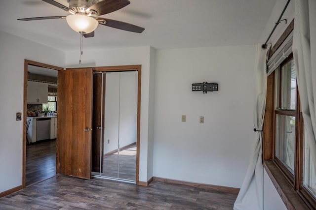 empty room with dark hardwood / wood-style flooring, a wealth of natural light, and ceiling fan