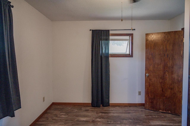 unfurnished room with dark hardwood / wood-style floors and a textured ceiling