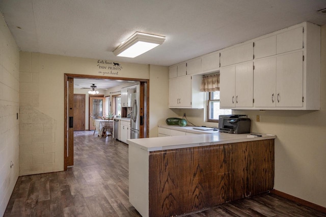 kitchen with white cabinets, stainless steel appliances, dark hardwood / wood-style flooring, kitchen peninsula, and ceiling fan