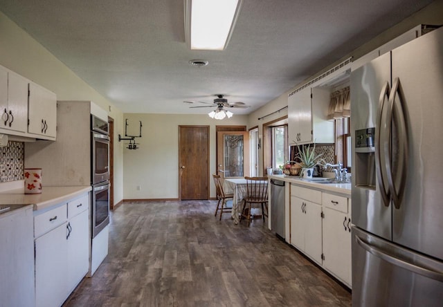 kitchen with a textured ceiling, dark hardwood / wood-style floors, stainless steel appliances, white cabinetry, and ceiling fan