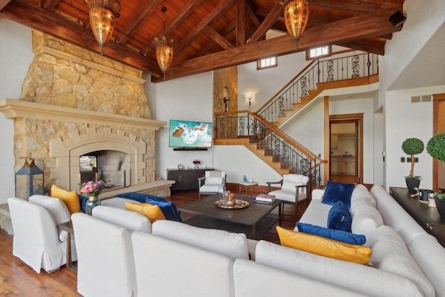 living room featuring a notable chandelier, a stone fireplace, hardwood / wood-style floors, wood ceiling, and high vaulted ceiling