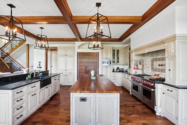 kitchen with hanging light fixtures, a chandelier, butcher block counters, a kitchen island, and dark hardwood / wood-style floors