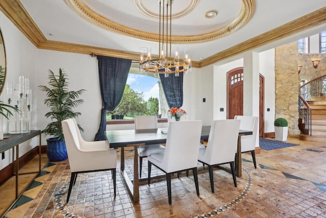 dining space with a raised ceiling, a notable chandelier, and ornamental molding