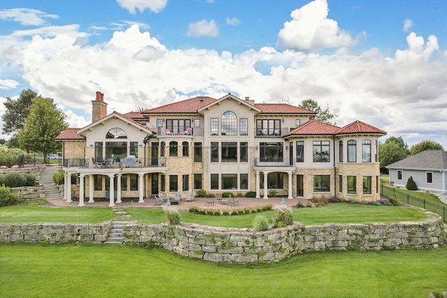 back of house featuring a lawn, a patio area, and a balcony