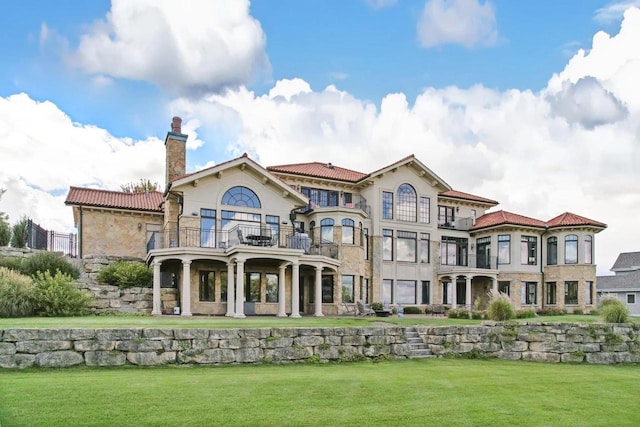 rear view of property featuring a lawn and a balcony