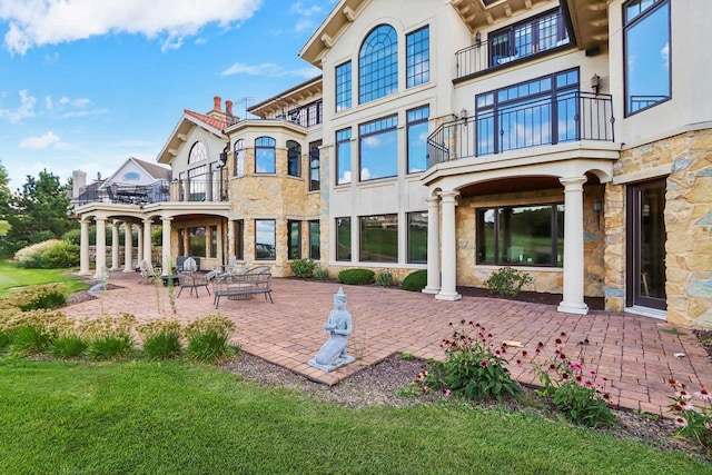 rear view of property featuring a yard, a patio area, and a balcony