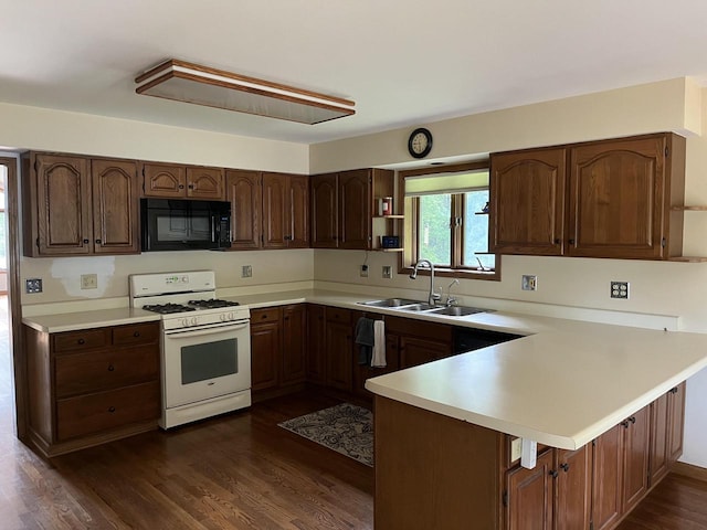 kitchen featuring kitchen peninsula, a kitchen breakfast bar, white range with gas cooktop, sink, and dark hardwood / wood-style floors