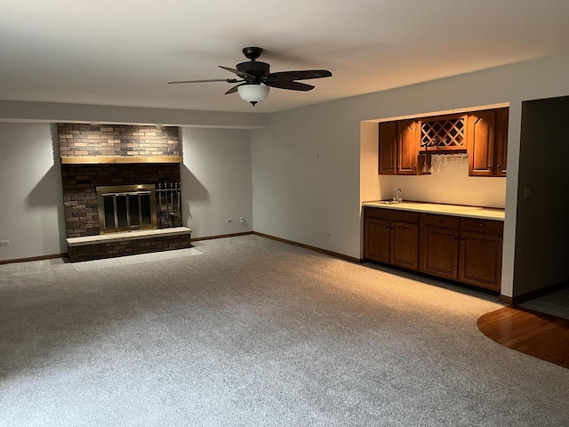 unfurnished living room with ceiling fan, a fireplace, light colored carpet, and wet bar