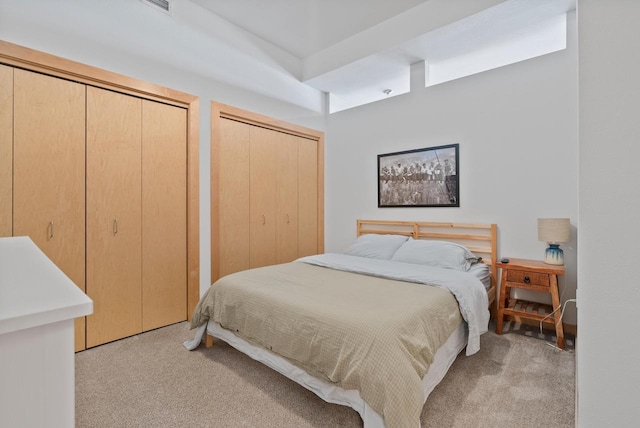 bedroom featuring two closets and light carpet