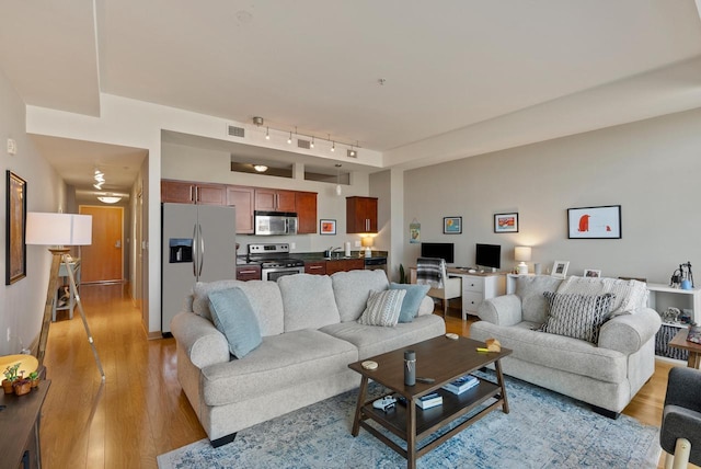 living room featuring track lighting, visible vents, and light wood-type flooring