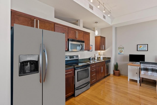 kitchen featuring visible vents, light wood finished floors, a sink, appliances with stainless steel finishes, and dark countertops