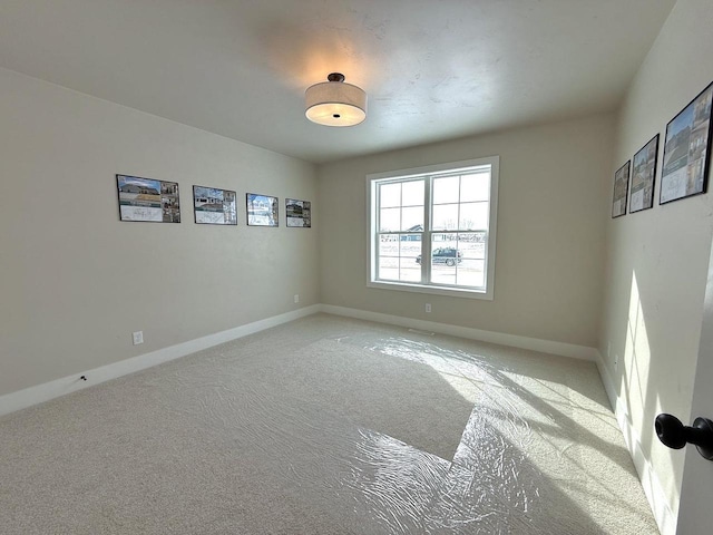 empty room featuring light carpet and baseboards