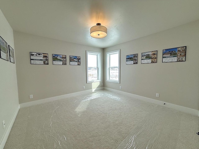 carpeted spare room featuring baseboards