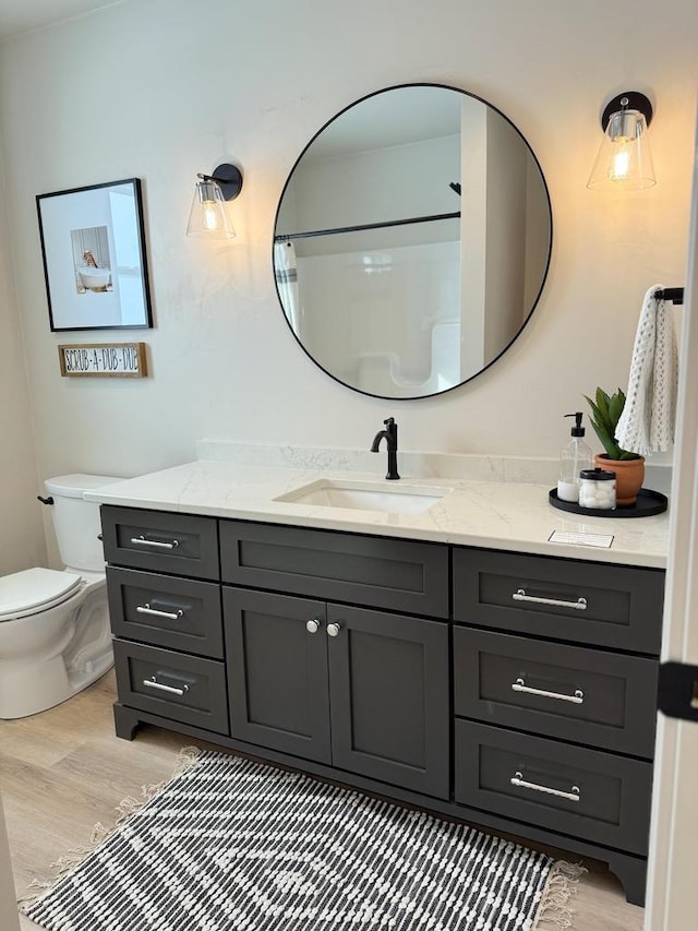 bathroom with walk in shower, vanity, toilet, and wood finished floors