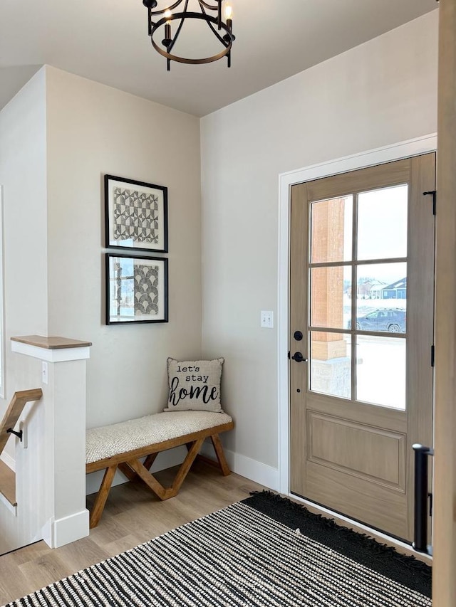 entryway with light wood-type flooring, baseboards, and a chandelier