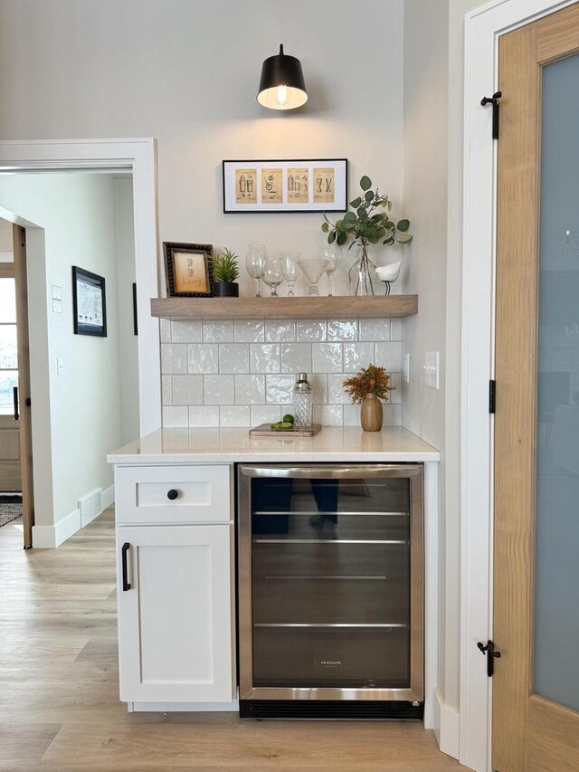 5090 N Cobble Creek Dr, Grand Chute, WI 54913 - indoor dry bar featuring beverage cooler, tasteful backsplash, light wood-style floors, and baseboards