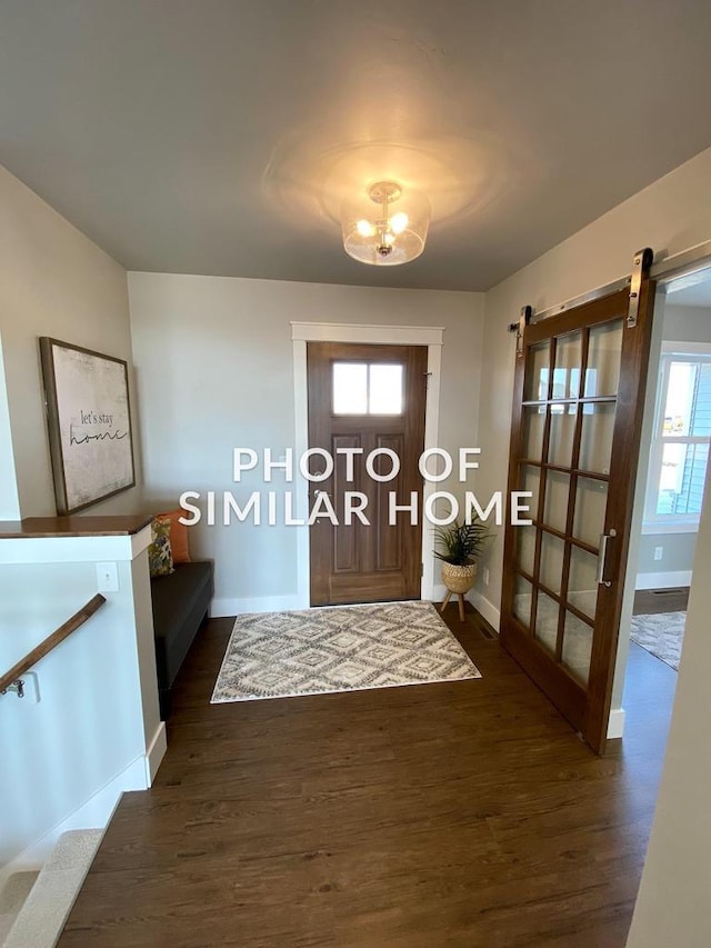 entryway with dark wood finished floors, baseboards, and a barn door