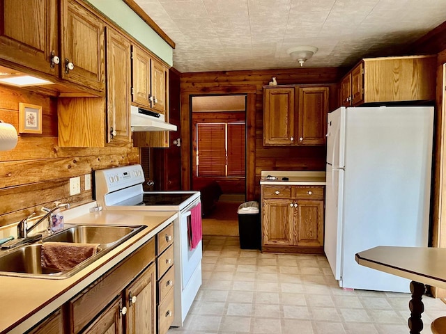 kitchen featuring sink, white appliances, and wooden walls