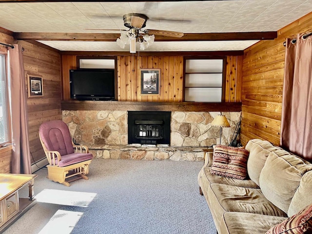 living room with ceiling fan, carpet floors, beam ceiling, and a stone fireplace