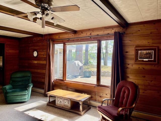 sitting room with light colored carpet, ceiling fan, wood walls, and beamed ceiling