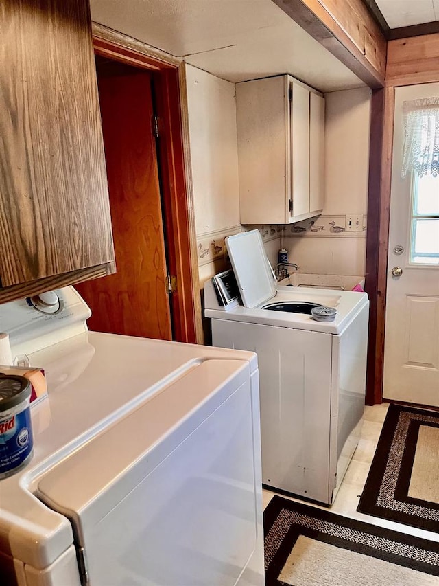 clothes washing area featuring cabinets, separate washer and dryer, light tile patterned floors, sink, and wooden walls