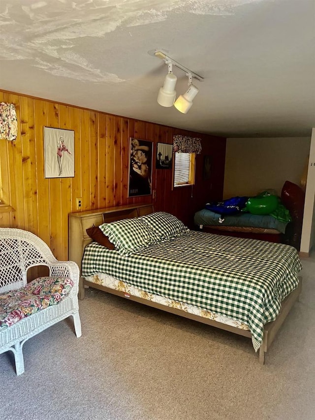 bedroom with track lighting, wood walls, a textured ceiling, and carpet floors