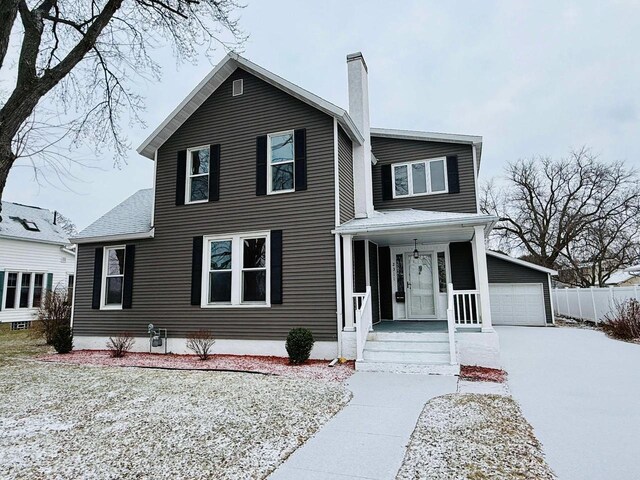 view of front of house with a front yard, a porch, a garage, and an outdoor structure