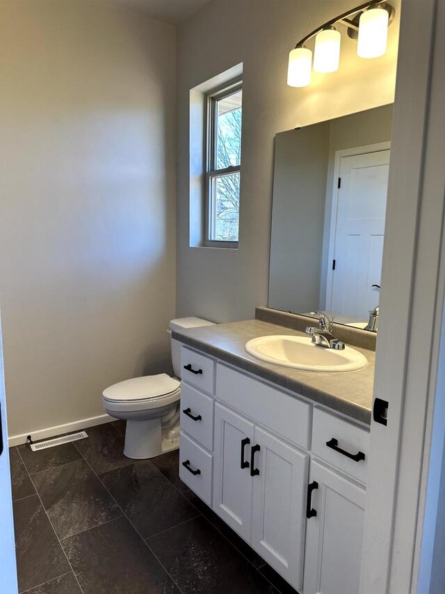 bathroom with vanity, toilet, and baseboards