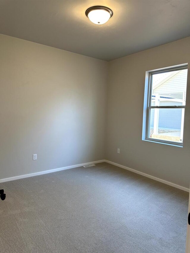 unfurnished room with baseboards and dark colored carpet