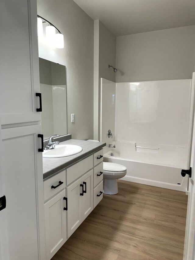 bathroom featuring bathing tub / shower combination, wood finished floors, vanity, and toilet