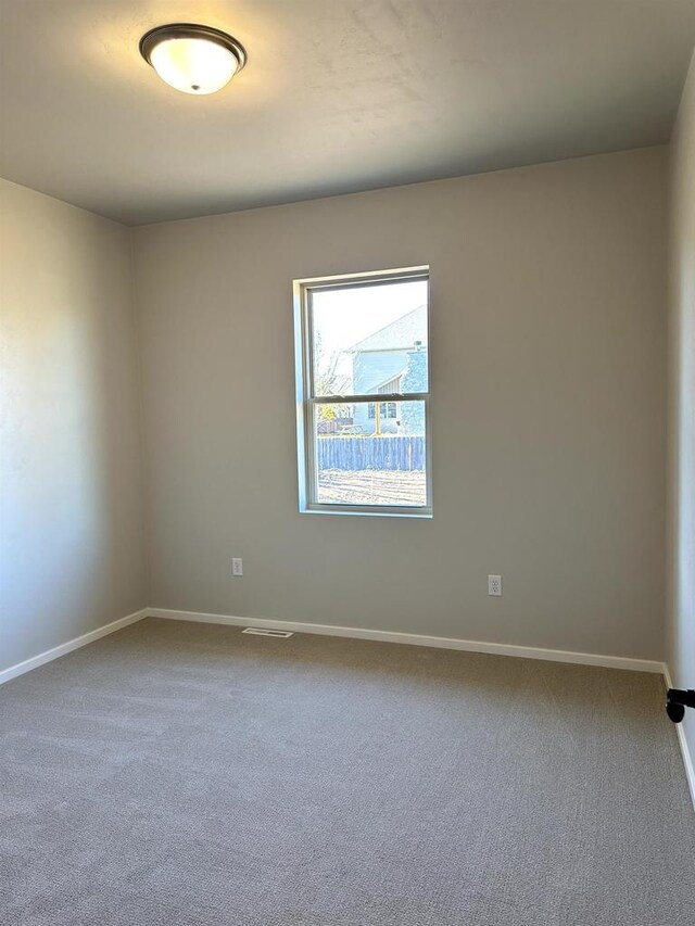 spare room with baseboards and carpet floors