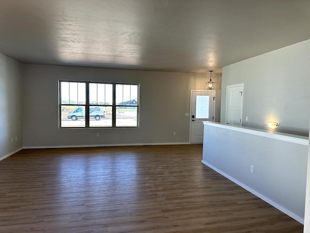 spare room featuring baseboards and dark wood-style floors