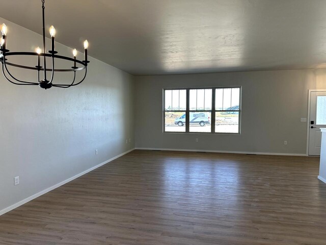 interior space with dark wood finished floors, an inviting chandelier, and baseboards